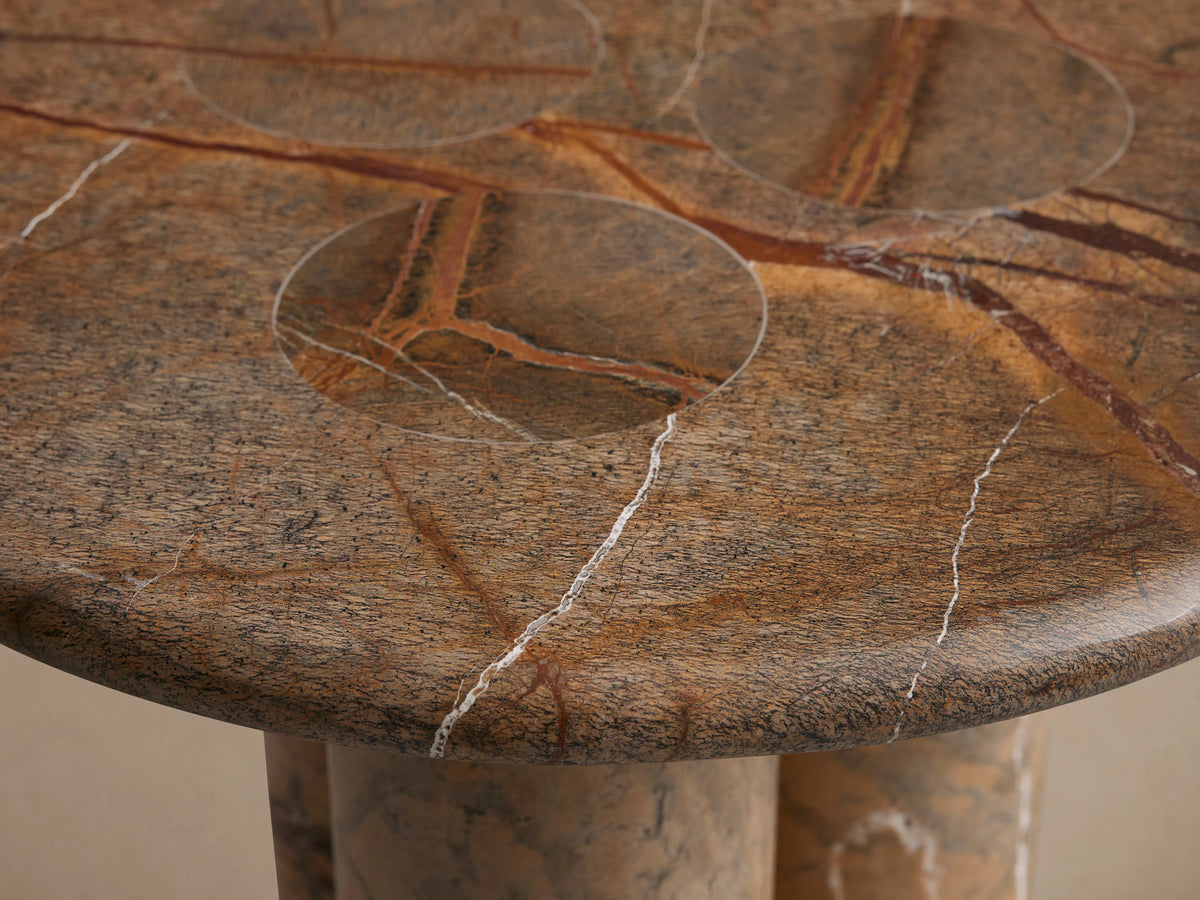 Serafin End Table made of natural stone with round top and two column legs, displaying unique veining and color variations.