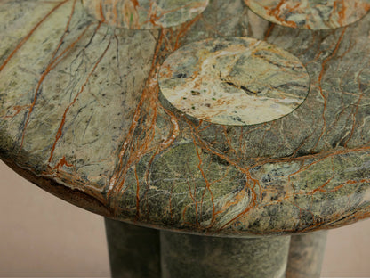 Front view of a green and brown marbled round table, featuring a circular top and three sturdy cylindrical legs.