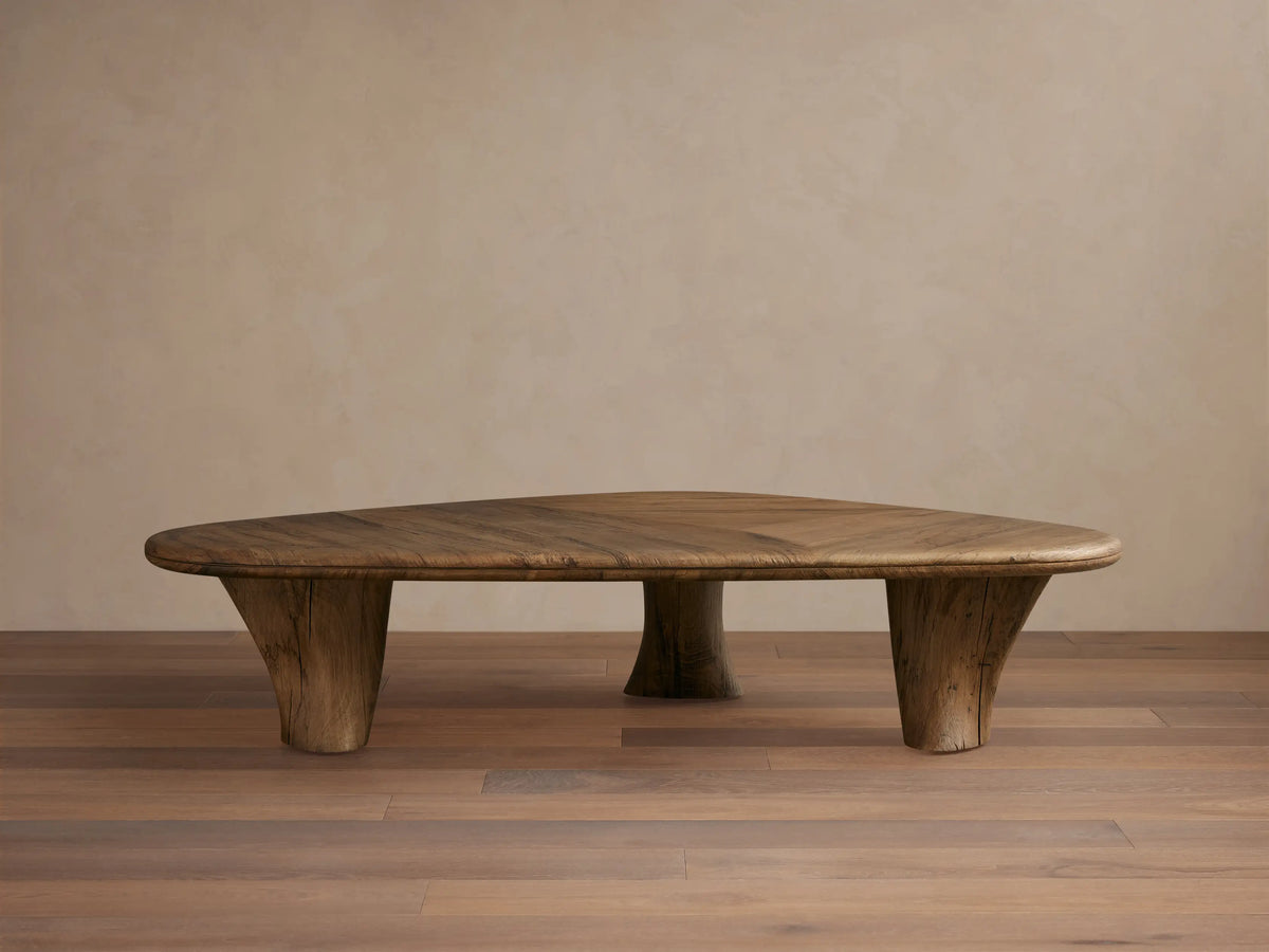 Soumaya Coffee Table: Organic, triangular spalted primavera wood coffee table with radial grain top, thick mahogany legs on wood floor.