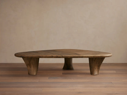 Soumaya Coffee Table: Organic, triangular spalted primavera wood coffee table with radial grain top, thick mahogany legs on wood floor.