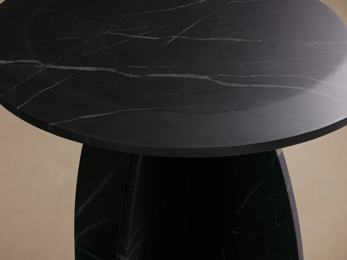 Solstice End Table with round black marble top and matching laminate legs, displaying white veining patterns against a neutral background.