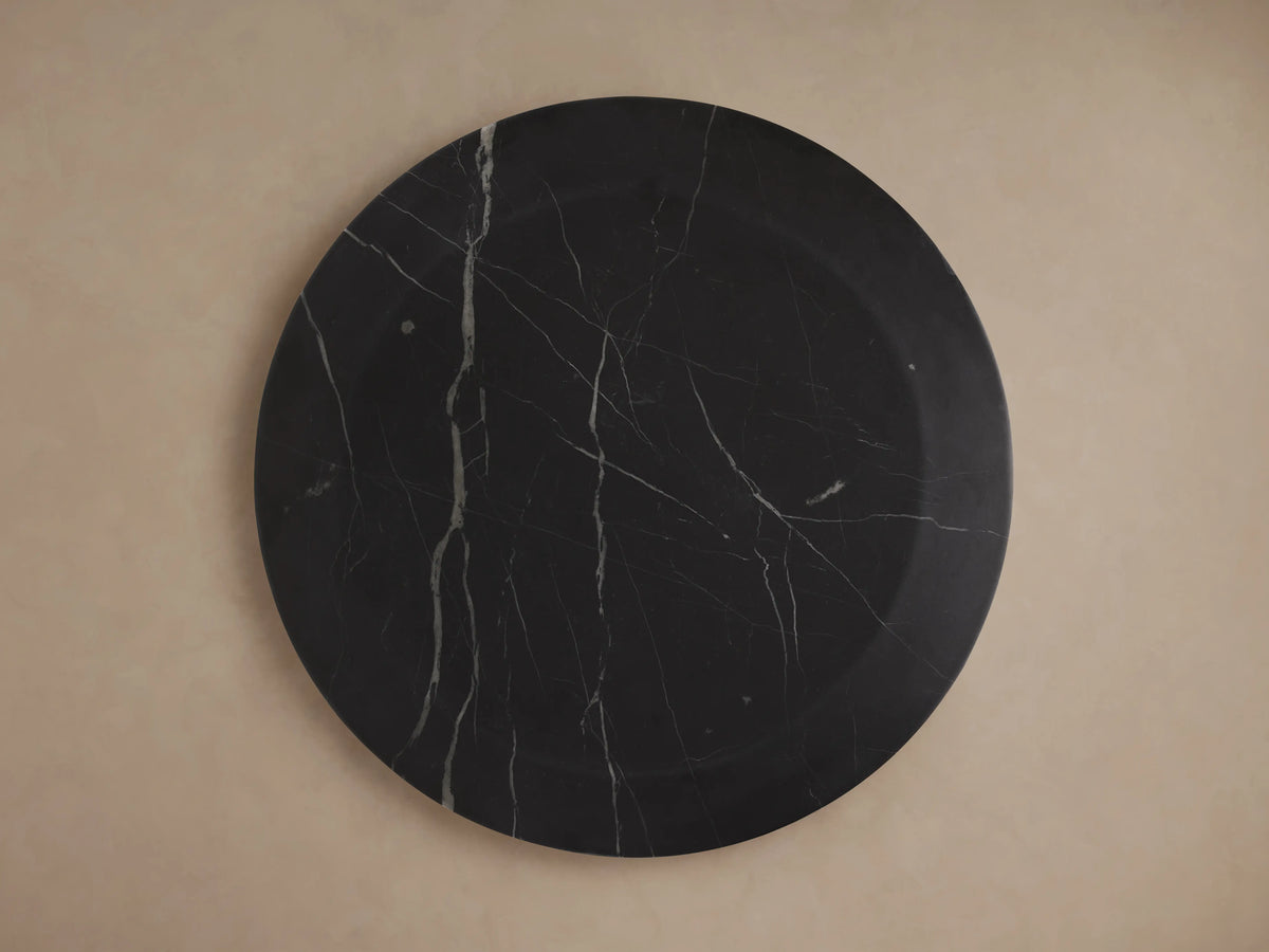 A round Solstice End Table with a smooth, dark Black Marquina marble surface featuring light vein patterns, viewed from above.