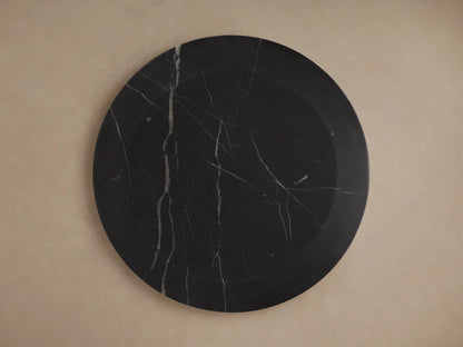 A round Solstice End Table with a smooth, dark Black Marquina marble surface featuring light vein patterns, viewed from above.