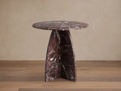 Solstice End Table in deep red marble with white veins, featuring a round top and curved, solid table legs.