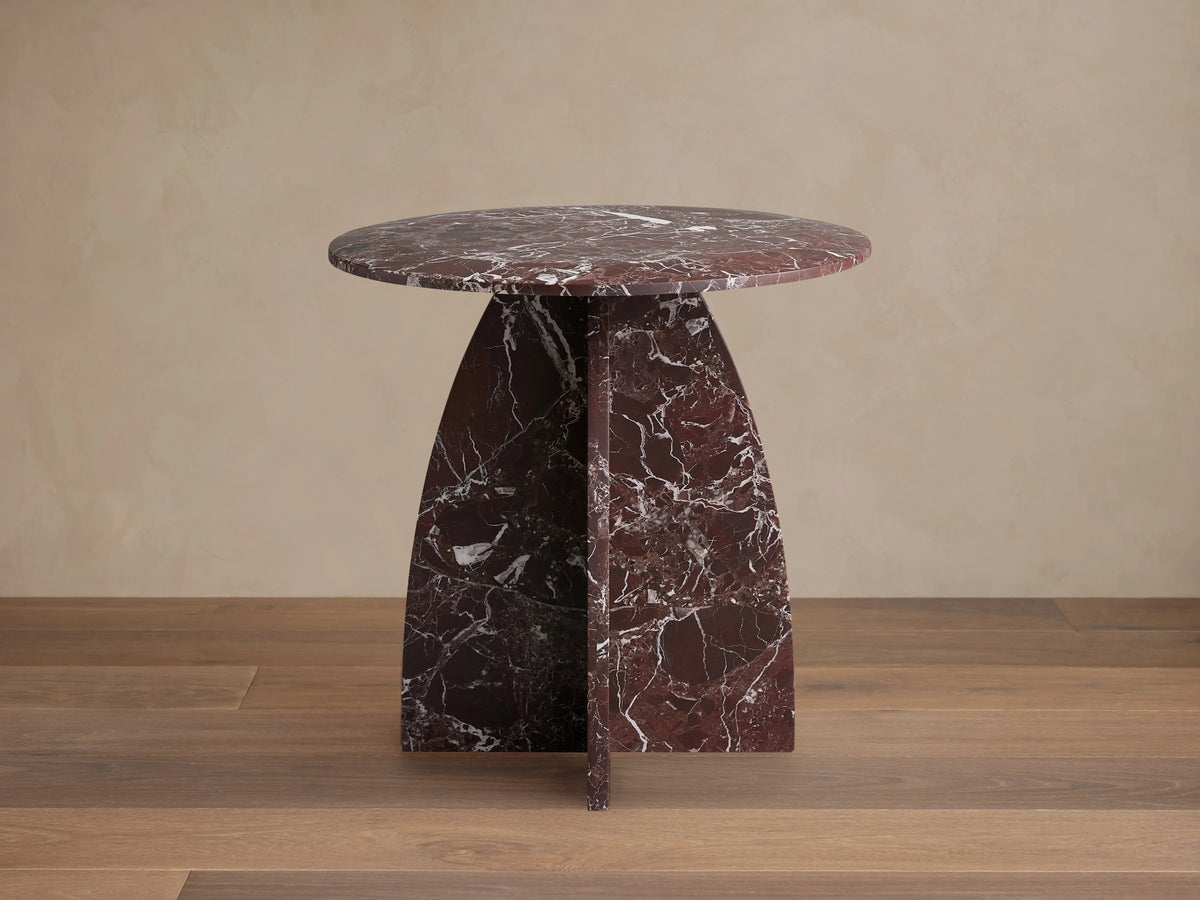 Solstice End Table in deep red marble with white veins, featuring a round top and curved, solid table legs.