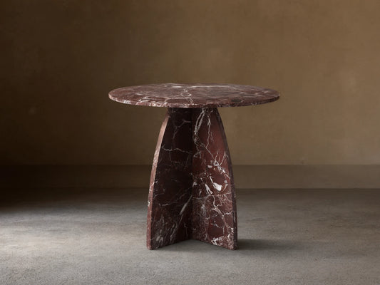 Solstice End Table in deep red marble with white veins, featuring a round top and curved, solid table legs.