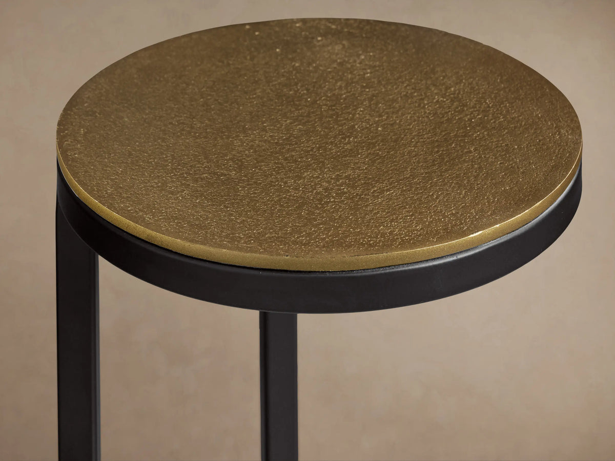 Front view of the Soma Martini Table, featuring a round gold top and a black metal frame with a circular base.