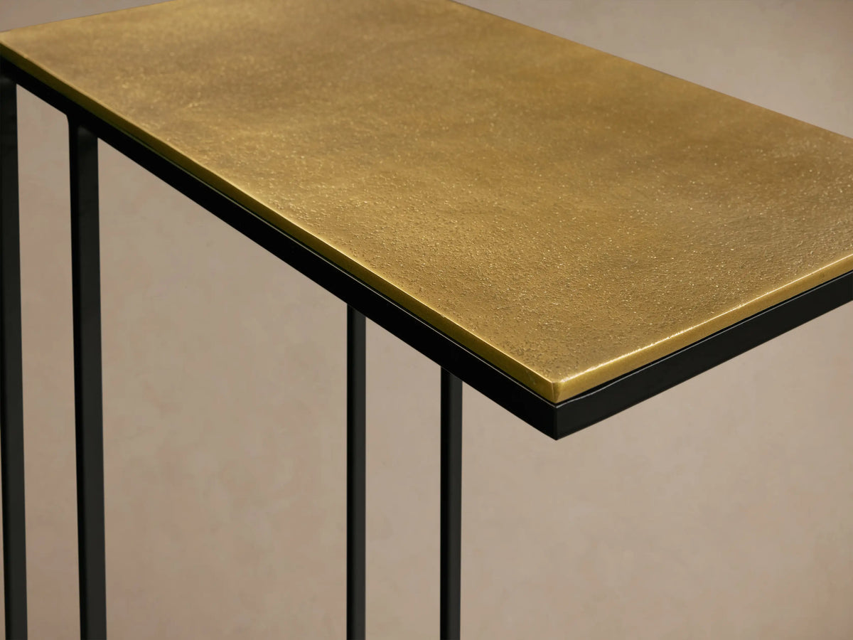 Close-up of the gold patinaed aluminum tabletop and black powder-coated stainless steel base of the Soma C Table.