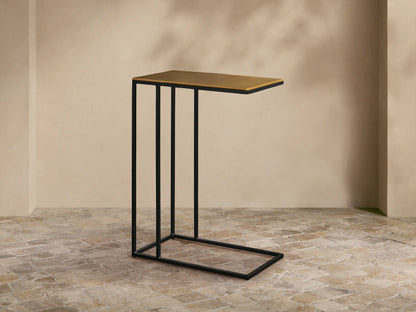Front-left view of the Soma C Table, featuring a gold rectangular top and a black C-shaped metal base.