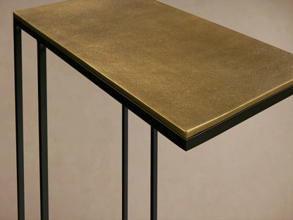 Close-up of the textured golden bronze aluminum tabletop and black powder-coated stainless steel frame of the Soma C Table.