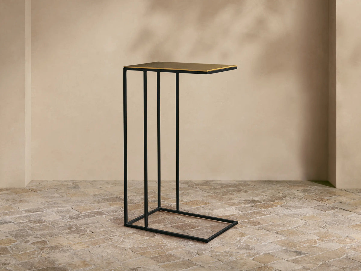 Front view of the Soma C Table featuring a black powder-coated stainless steel C-shaped base and a gold patinaed aluminum tabletop.