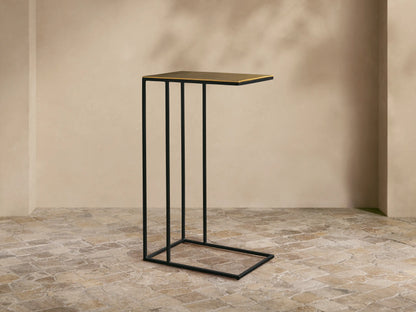 Front view of the Soma C Table featuring a black powder-coated stainless steel C-shaped base and a gold patinaed aluminum tabletop.