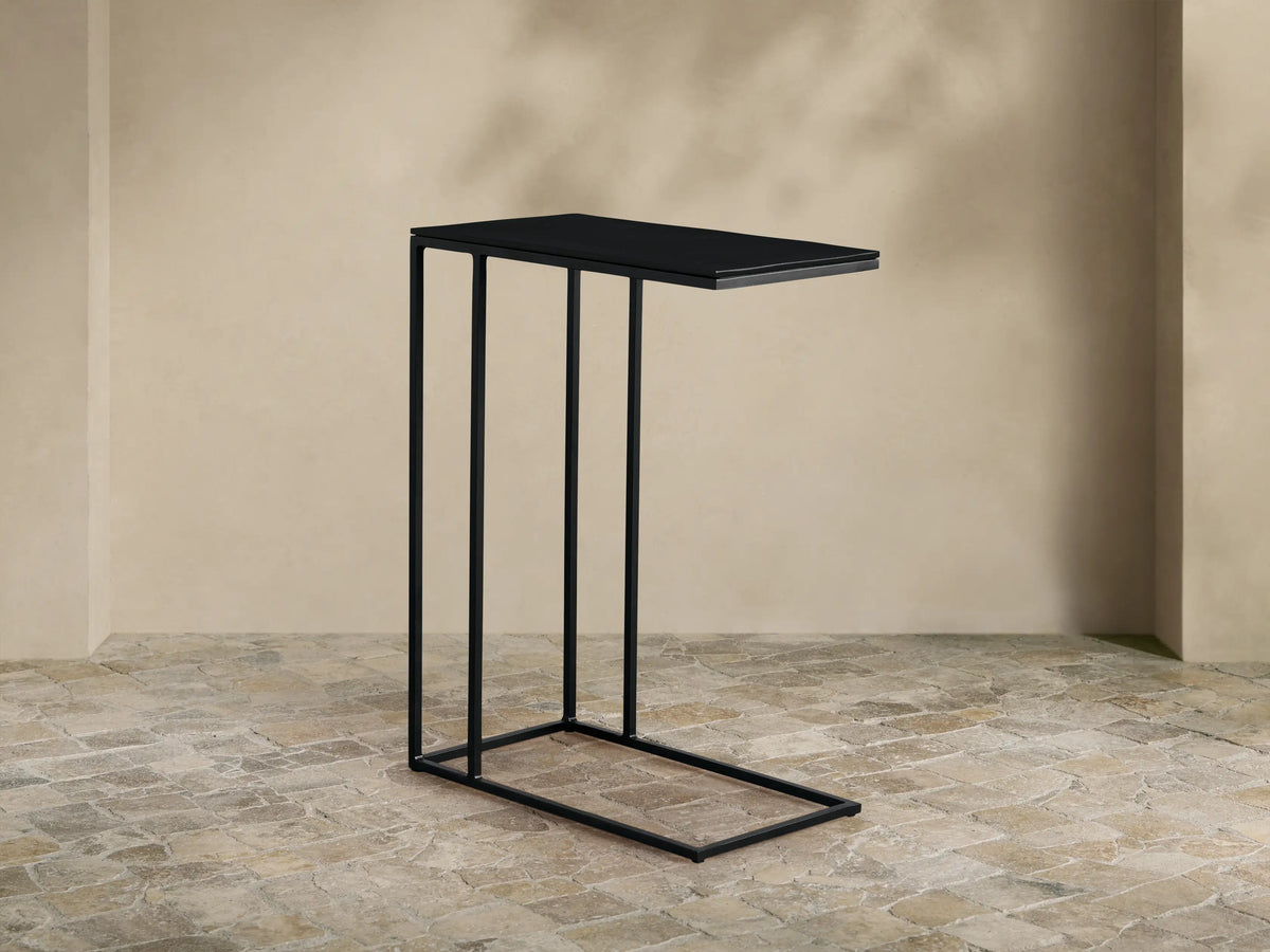 Black Soma C Table with a thin rectangular top and C-shaped base, featuring a minimalist design, against a neutral wall.