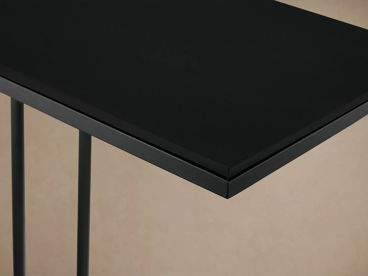 Black Soma C Table with rectangular patinaed aluminum top & powder-coated stainless steel frame, on a wood floor.