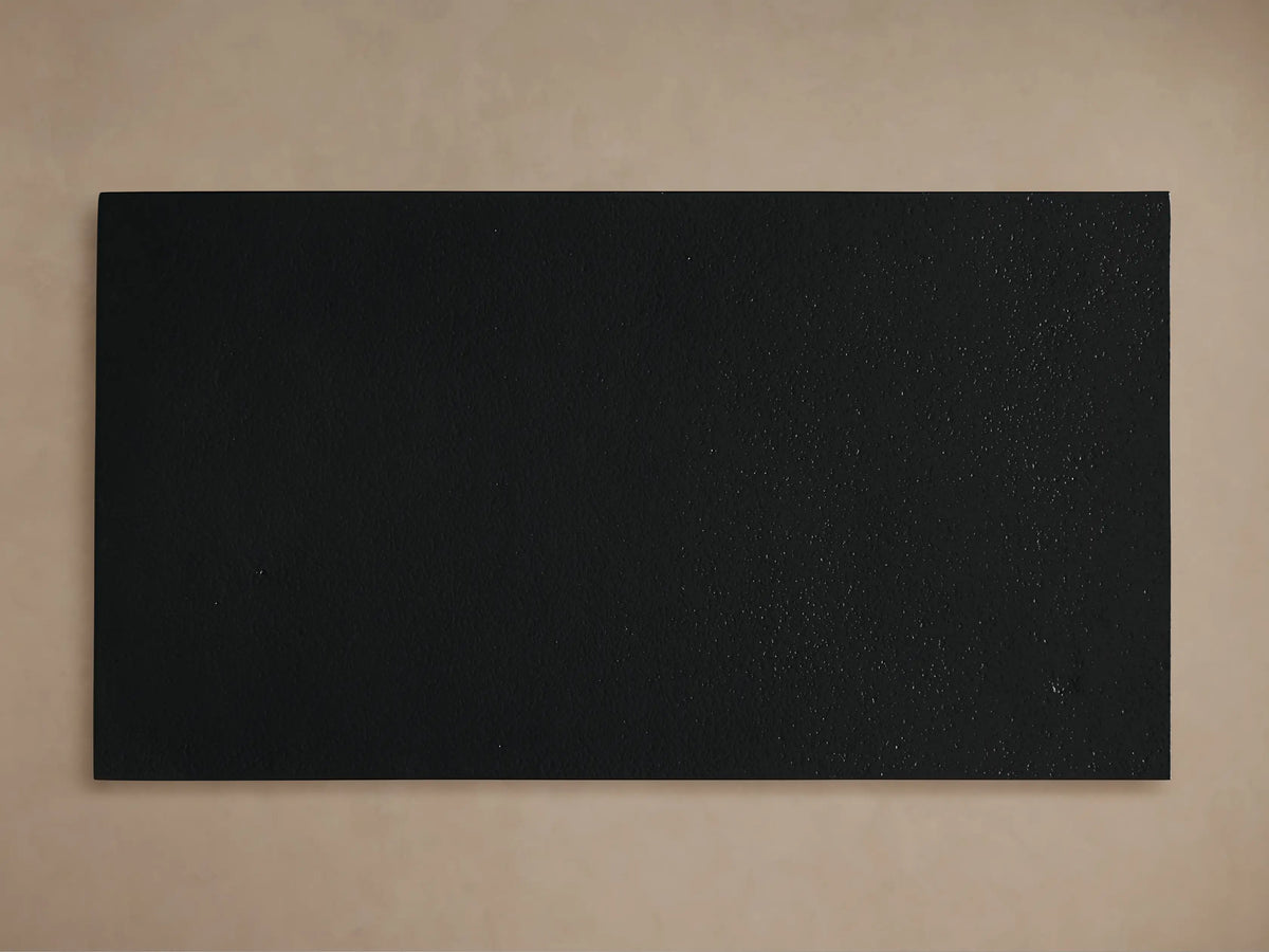 Close-up of Soma C Table's matte black tabletop with dark frame & legs, angled against a light beige background.