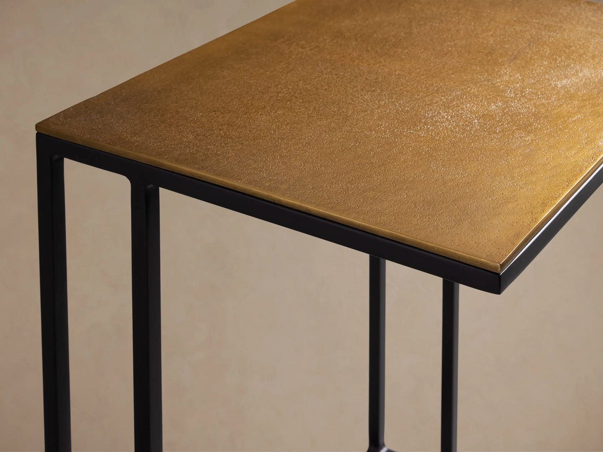 Soma Wide C Table: Patinaed light brown top on black C-shaped metal frame, on wood floor.
