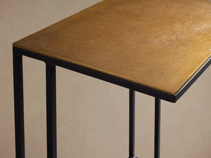 Soma Wide C Table: Patinaed light brown top on black C-shaped metal frame, on wood floor.