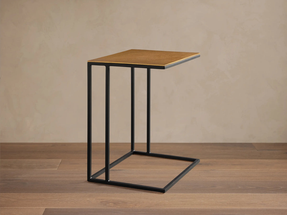 Close-up of Soma Wide C Table. Rectangular, textured gold patinaed aluminum top on black powder-coated steel frame.