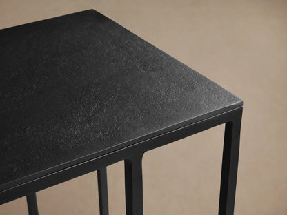 Black Soma C Table with a rectangular top and minimalist 'C' shaped frame, on a wood floor against a neutral wall.