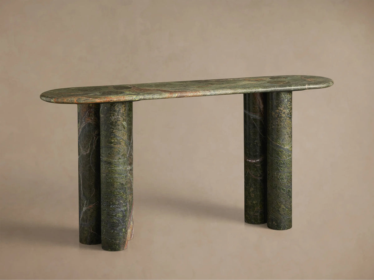 Close-up of a green marble table with reddish-brown and white veins, rounded edges, two circular depressions, and cylindrical legs.