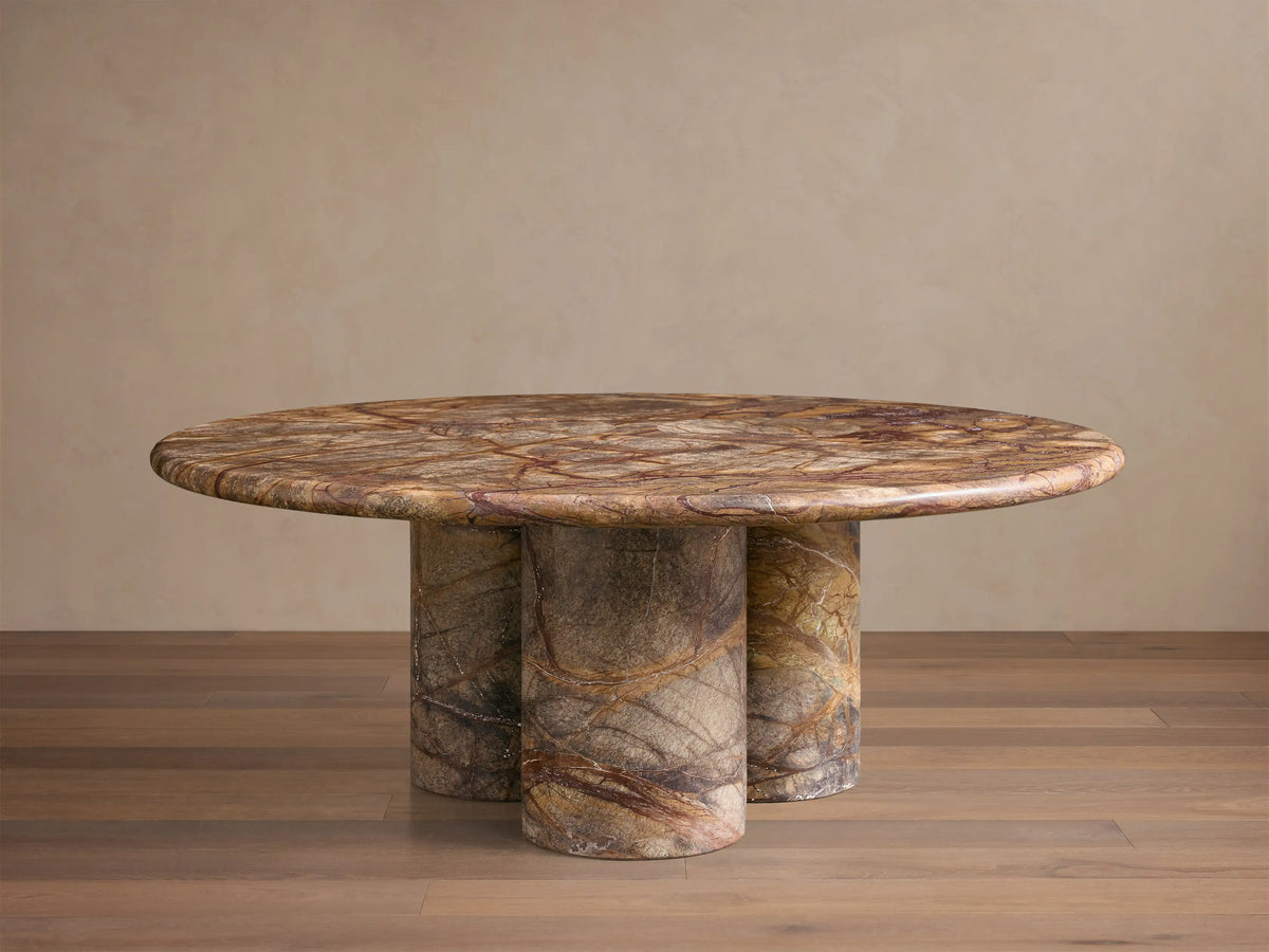 Front view of Serafin Coffee Table. Round marble top with green, brown, and red veining, on three cylindrical marble legs.