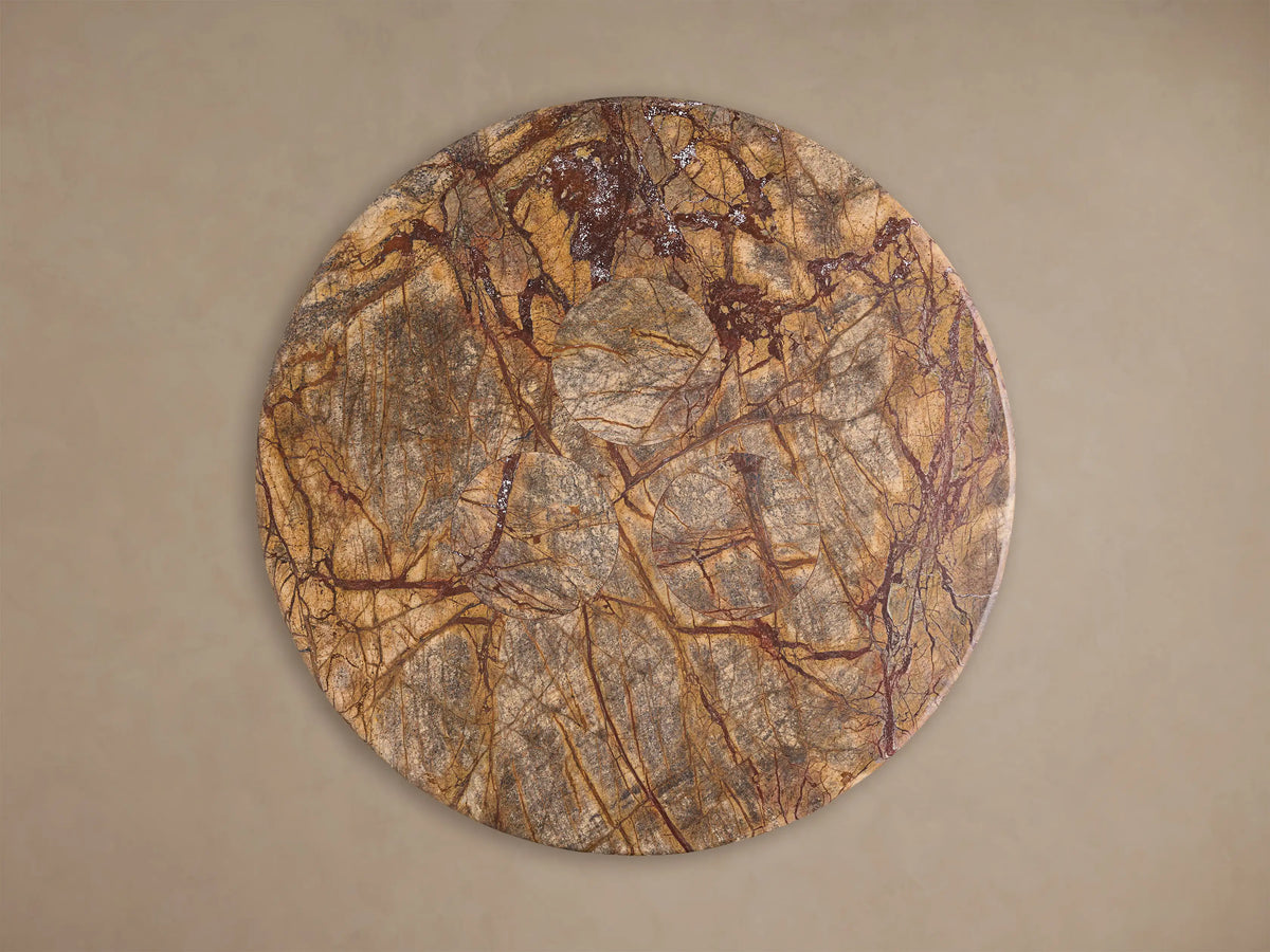 Front view of Serafin Coffee Table. Round marble top with green, brown, and red veining, on three cylindrical marble legs.