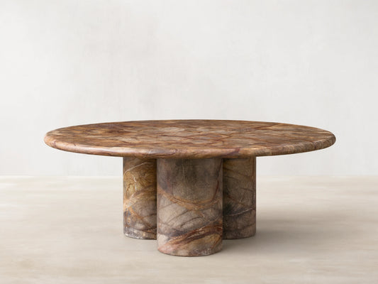 Front view of Serafin Coffee Table. Round marble top with green, brown, and red veining, on three cylindrical marble legs.