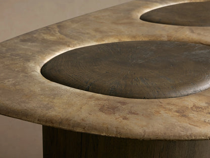 Sucurro Coffee Table: Elongated, mottled bronze-toned aluminum top with 2 recessed ovals, on 2 dark wood bases.