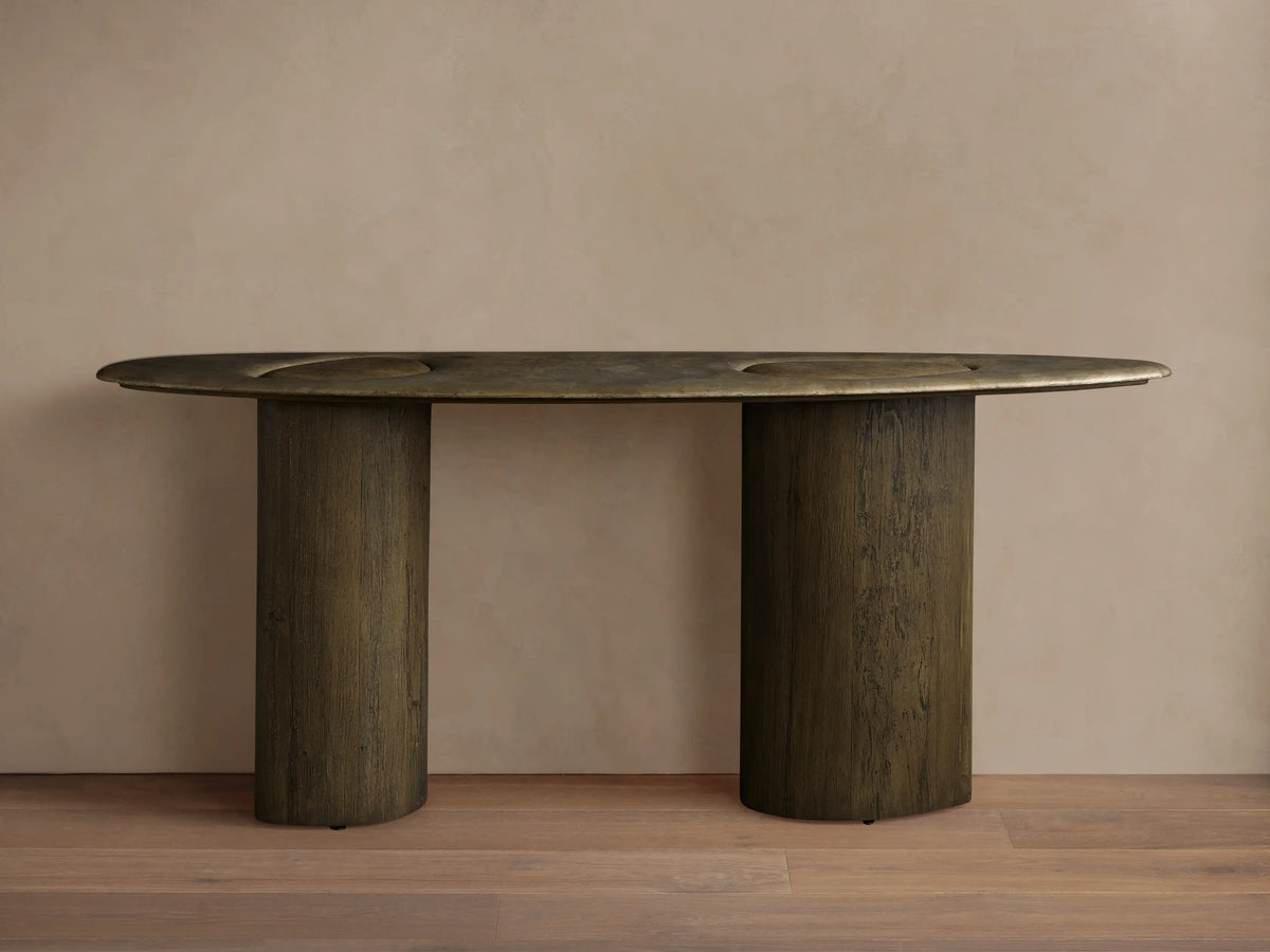 Sucurro Console Table: Dark oval oxidized aluminum top with recessed shapes & dimples, two thick cylindrical spalted wood bases.