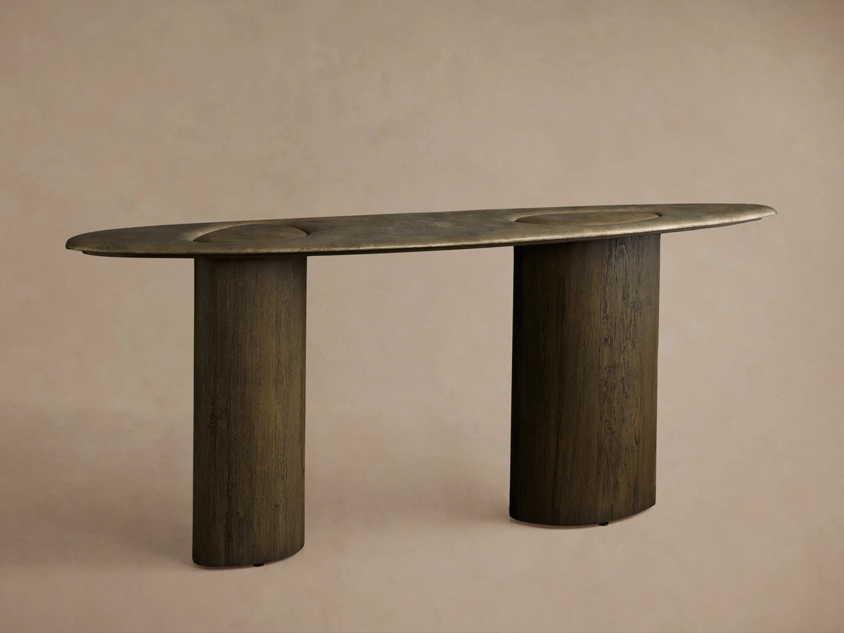 Sucurro Console Table: Dark oval oxidized aluminum top with recessed shapes & dimples, two thick cylindrical spalted wood bases.