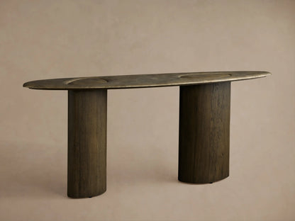 Sucurro Console Table: Dark oval oxidized aluminum top with recessed shapes & dimples, two thick cylindrical spalted wood bases.