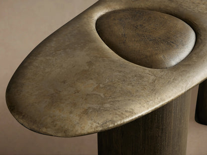 Sucurro Console Table. Oval weathered aluminum top with two dimpled indents, resting on two dark brown wood cylindrical legs.