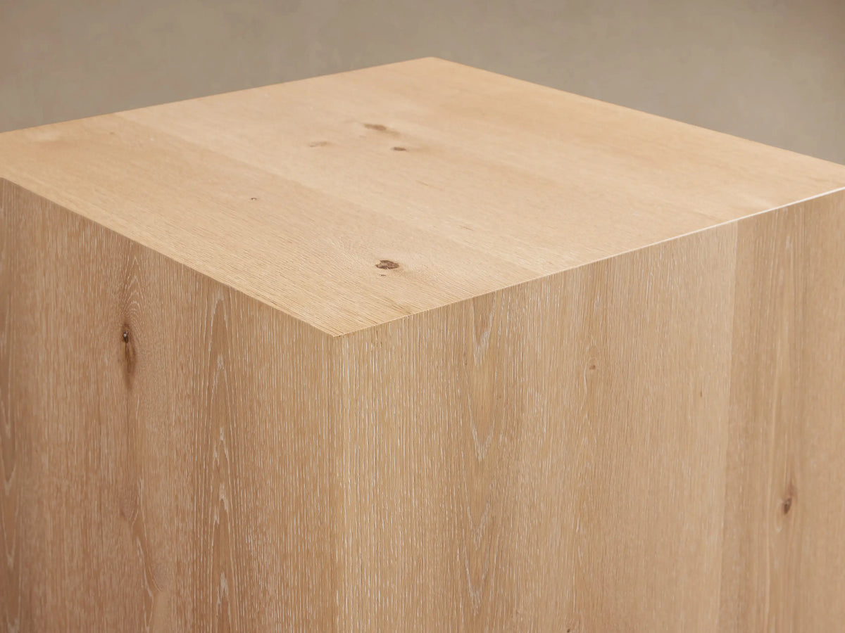 Sullivan End Table made of light oak wood featuring visible grain patterns and knots, resting on a black plinth-style base.