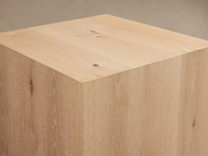 Sullivan End Table made of light oak wood featuring visible grain patterns and knots, resting on a black plinth-style base.