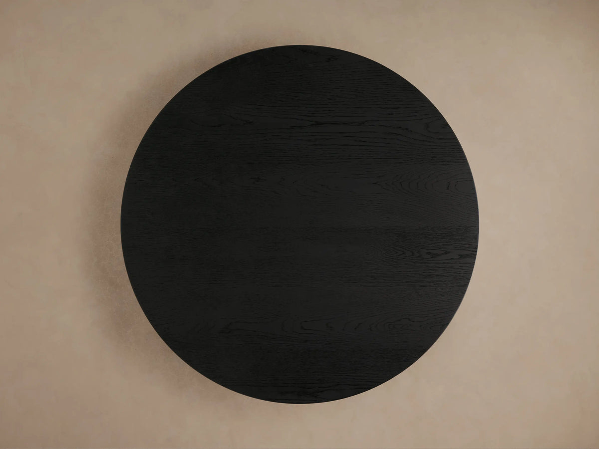 Sullivan Round Coffee Table with dark oak wood grain texture, rounded edge, and black plinth base, shown in close-up.