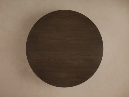 Round Sullivan Coffee Table crafted from dark European oak, showcasing natural wood grain patterns and resting on a black plinth-style base.