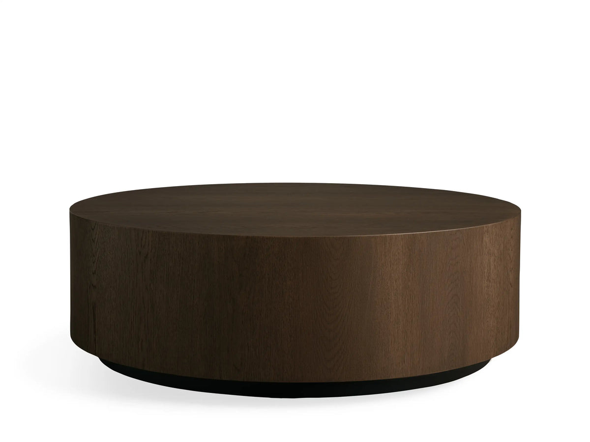 Sullivan Round Coffee Table, top view. Dark wooden tabletop with visible grain patterns, resting on a black base, set against a neutral background.