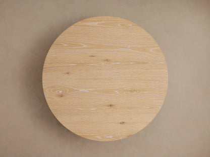 Sullivan Round Coffee Table in light European oak, featuring natural wood grain, knots, and a smooth matte finish on a black base.