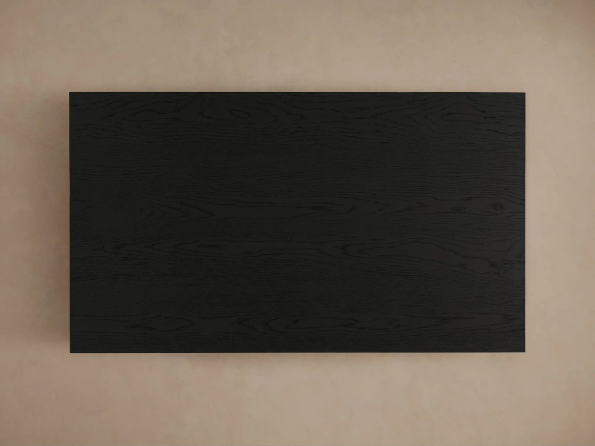 Sullivan Coffee Table with a close-up view of the black, wooden plinth-style base, showing natural oak grain patterns and textures.