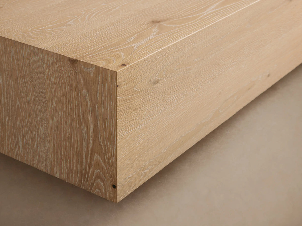 Sullivan Coffee Table made of light European oak with natural cracks and knots, resting on a black plinth-style base.