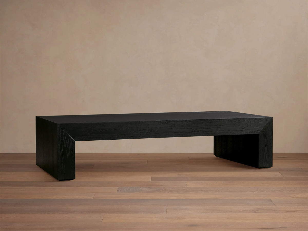 Sullivan Waterfall Coffee Table in dark oak finish, showcasing a smooth, elongated surface with seamless waterfall edges on a wooden floor.