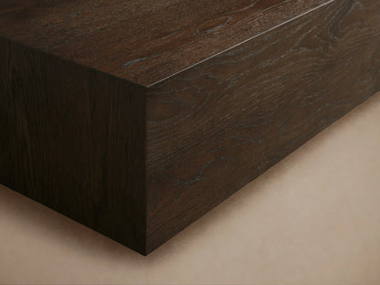 Sullivan Coffee Table made of solid oak with a dark finish, featuring a rectangular top and a black plinth-style base on wooden floor.