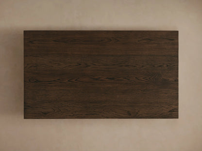 Sullivan Coffee Table close-up showing solid oak with visible grain patterns and a black, plinth-style base on a neutral background.