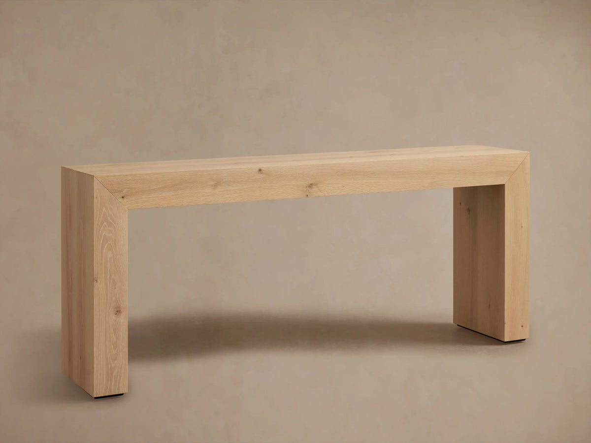 Sullivan Console Table in a light oak finish, showcasing waterfall edges and natural wood grain, topped with a vase and book.