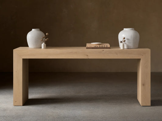 Sullivan Console Table in a light oak finish, showcasing waterfall edges and natural wood grain, topped with a vase and book.