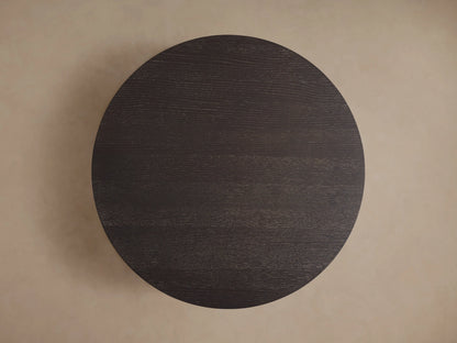 Round coffee table in dark Northman Cinder finish viewed from above, showing the smooth, rich wood grain texture.