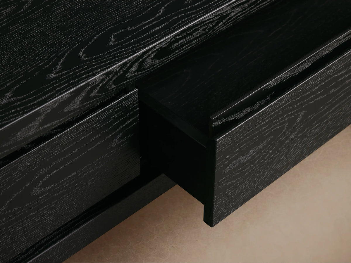 Sullivan Storage Coffee Table made of black oak with plinth-style base, showing two discreetly integrated soft-close drawers.