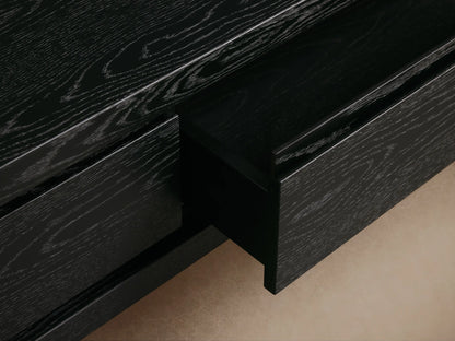 Sullivan Storage Coffee Table made of black oak with plinth-style base, showing two discreetly integrated soft-close drawers.