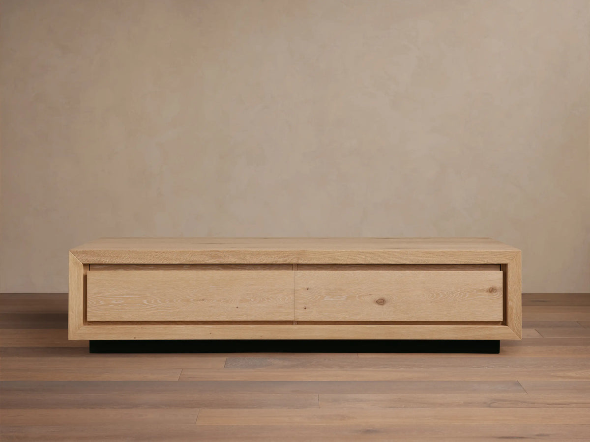 Sullivan Storage Coffee Table made of natural European oak with visible cracks and knots, on a black plinth base, front view.