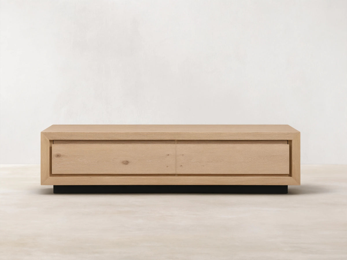 Sullivan Storage Coffee Table made of natural European oak with visible cracks and knots, on a black plinth base, front view.